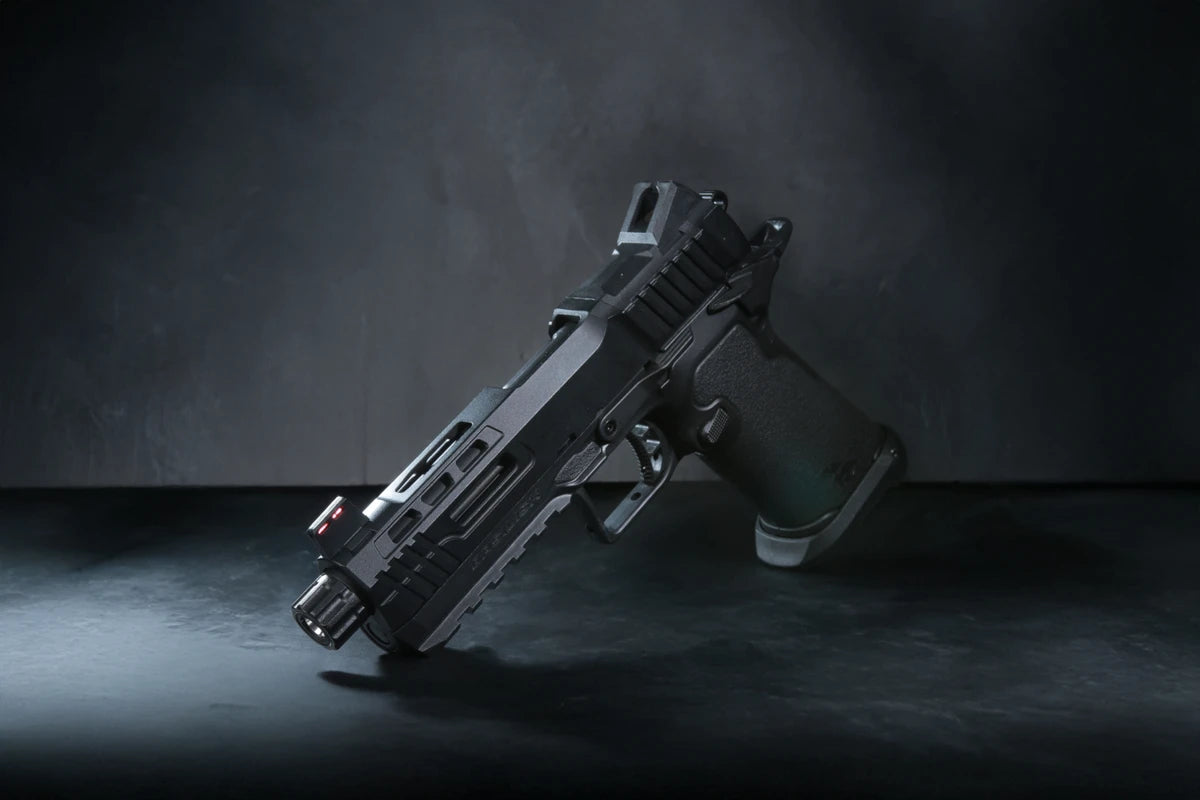 A semi-automatic airsoft pistol, identified as a Kizuna Works Basilisk shown on a dark, textured studio surface.